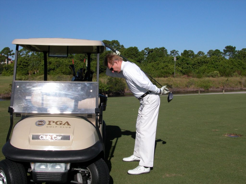 golfer stretching by golf cart