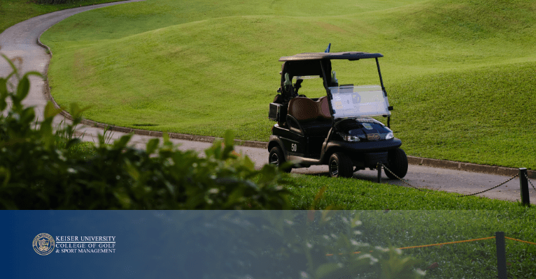 Black golf cart parked near a fairway on a golf course with green hills in the background.