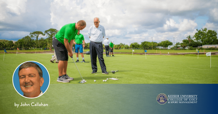 Golf student practicing putting while instructor observes on outdoor green at Keiser University College of Golf.