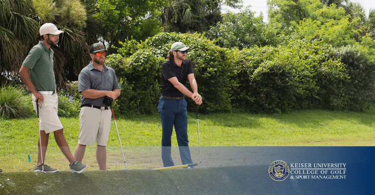Three golfers standing near tee box watching a shot during a round on a sunny golf course.