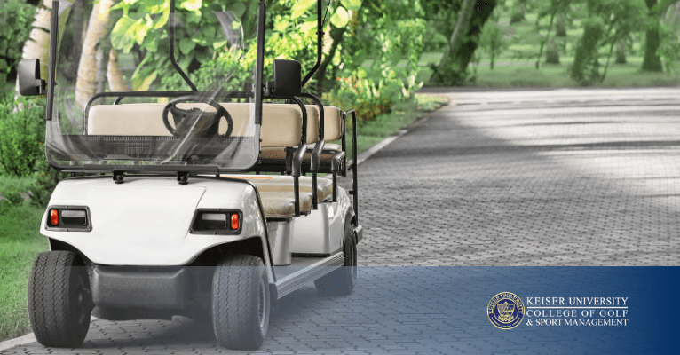 Golf cart parked on a paved course path surrounded by trees and greenery.
